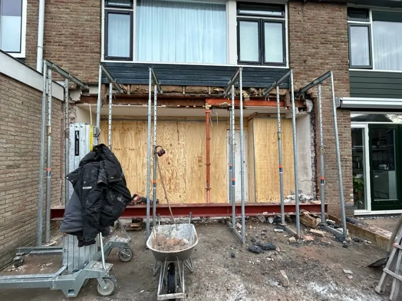 Aanbouw in uitvoering met een stalen balk en stempels achter een rijtjeswoning