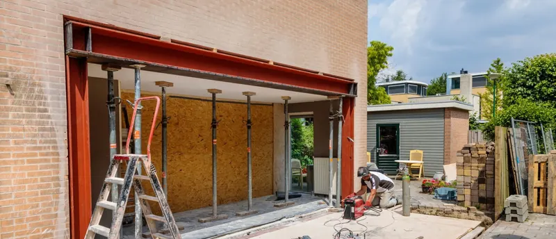 Stalen balk boven een nieuwe gevelopening, ondersteund met stempels